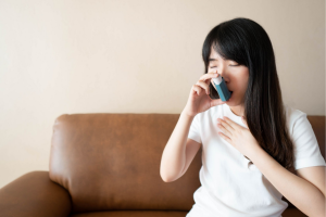 asian woman using blue inhaler for asthma attack