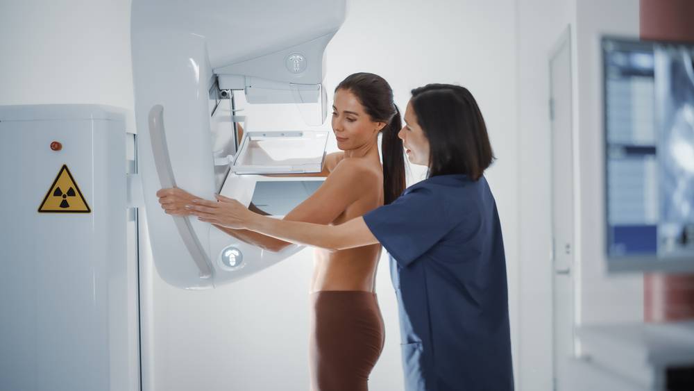 Friendly,Female,Doctor,Explains,The,Mammogram,Procedure,To,A,Topless