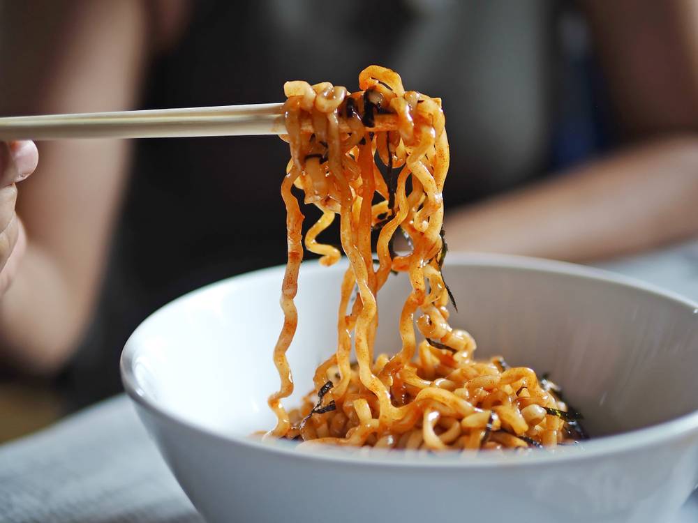 Woman,Eating,Instant,Noodles,With,Wooden,Chopsticks,On,Blurred,Background