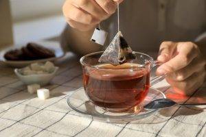 Woman,Taking,Tea,Bag,Out,Of,Cup,At,Table,Indoors,